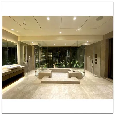 This is the epitome of a spa-inspired bathroom. The central jacuzzi, surrounded by glass, looks out onto a private garden, creating an immersive experience that combines the luxury of a spa with the serenity of nature.