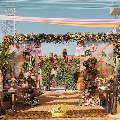 A beautiful entrance for an Assamese-themed Haldi, featuring a lush sunflower garland, traditional Jaapis, and hanging Gamchas. It's a vibrant and heartfelt welcome.