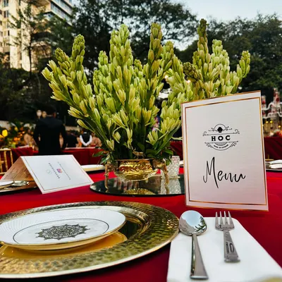 For this exclusive event, we designed a regal tablescape featuring rich red linens and gleaming gold charger plates. The custom menu card and elegant floral arrangements create an atmosphere of pure opulence, setting the stage for a memorable dining experience.