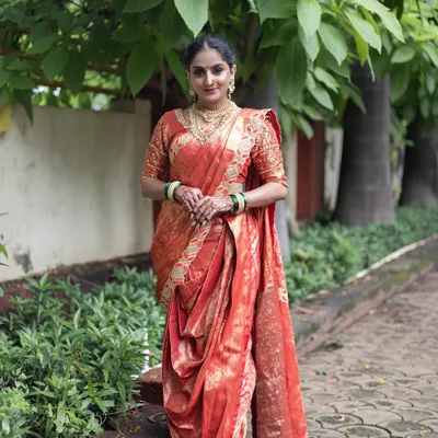 A full length view of a traditional red and gold Nauvari saree. This is a classic look for a Maharashtrian bride, complete with green bangles.