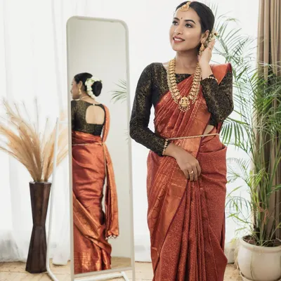 A professionally styled shot featuring a modern take on a traditional look. The makeup is clean and luminous, complementing the rich color of the saree and the contemporary setting.