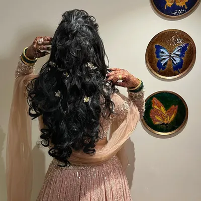 Hair goals! A beautiful half-up, half-down style with voluminous curls and delicate floral accessories, perfect for a sangeet or reception.