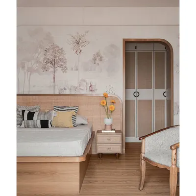 This master bedroom features a custom cane headboard set against a soft, tropical pastel wallpaper. An arched doorway with rounded cane-shutter doors leads to the walk-in wardrobe, adding a touch of warmth and modern minimalism.