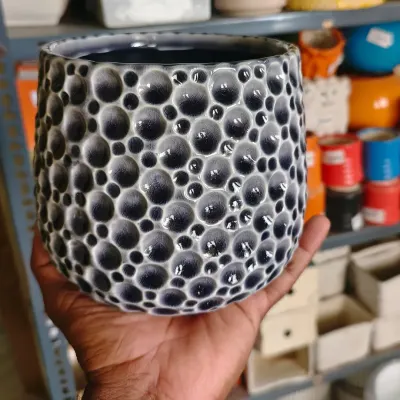 This 6-inch imported ceramic pot features a unique bubble texture in a deep blue-grey glaze. It's a heavy, high-quality planter that adds a touch of sophistication to any indoor plant.
