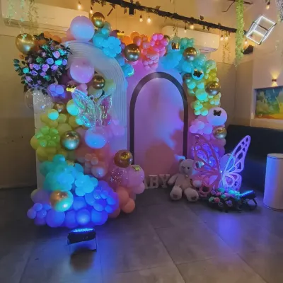 A magical, fairytale-themed decoration with rainbow lighting. This enchanting setup features glowing butterfly wings, a teddy bear, and a colorful balloon arch, creating a truly unique and dreamy atmosphere.