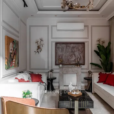 This living room is a study in classic elegance, featuring a custom-designed natural stone fireplace as the focal point. We used wall mouldings and a refined color palette, adding warmth with pops of red in the cushions for a timeless yet inviting feel.