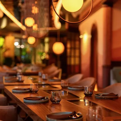 The view down our main dining hall in Mumbai, set for an evening of conversation and connection. The long wooden tables and soft, spherical lighting create a warm and inviting atmosphere for large group dinners.