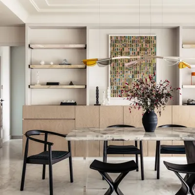 Introducing Apartment O2, a home where every corner invites warmth and happiness. The dining area features a stunning marble table with a unique glass and wood base, reflecting the family's creative spirit and love for playful design.