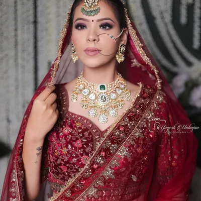 The kind of bridal beauty that turns heads and tells stories. This regal look, with its rich red velvet, intricate jewellery, and confident gaze, is rooted in tradition and designed to be unforgettable.