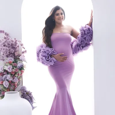 A vision in lavender. This dramatic mermaid gown with ruffled sleeves makes a stunning statement, complemented by the floral arrangement for a touch of fairytale elegance.