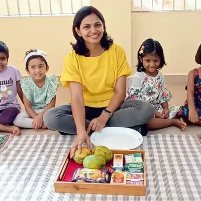 We're all set for our mango cheesecake activity. I guide the children as they get ready to explore ingredients and learn through this exciting fireless cooking project.