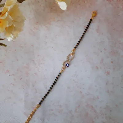 Protection meets elegance with this evil eye mangalsutra bracelet. It features an infinity symbol encrusted with crystals and a small evil eye, blending modern style with traditional meaning.