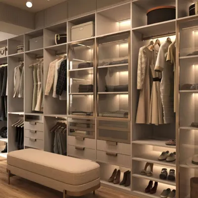 A spacious and well-organized walk-in closet with a neutral color palette. The design features a mix of hanging space, drawers, and open shelving with integrated lighting to illuminate clothing and accessories.