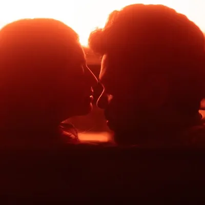 A powerful silhouette of the couple about to kiss, illuminated by a dramatic red light from within a car. This shot is pure cinema, focusing on the anticipation and intensity of the moment.