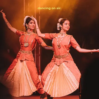 Two classical dancers strike a synchronized pose under warm stage lights. This shot, edited with a cinematic feel, captures the grace and precision of traditional Indian performance art.