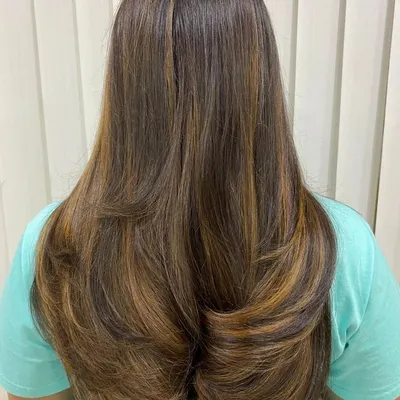 This layered haircut with warm balayage highlights is a perfect example of student work. We teach you how to combine cutting and coloring techniques to create a seamless, professional look.