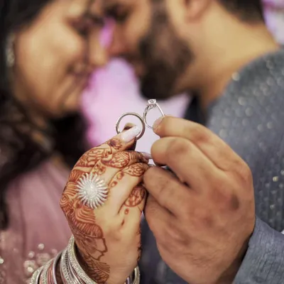The pivotal moment of the engagement, captured in a close-up of the couple holding their rings before the exchange.