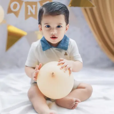 A sweet portrait for a first birthday celebration. The simple setup with a "ONE" banner and a balloon keeps the focus on the birthday boy's adorable expression.