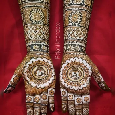 A beautiful design for a ring ceremony, featuring the couple's initials 'D' and 'A' inside ornate mandalas. The use of white henna for highlights adds a unique, modern touch.