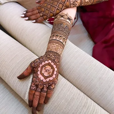 A beautiful full-arm design personalized with the couple's initials "NP" inside a floral mandala on the palm.
