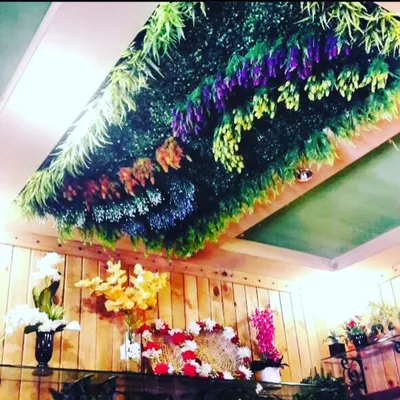A full artificial garden panel installed directly onto the ceiling. This design uses a mix of hanging flowers and ferns to create a colorful, upside-down meadow effect.