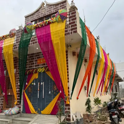 Make your home look festive with our exterior decoration services. Here, we've used long, flowing drapes in auspicious colors like yellow, pink, and green to adorn the front of the house for a wedding celebration.