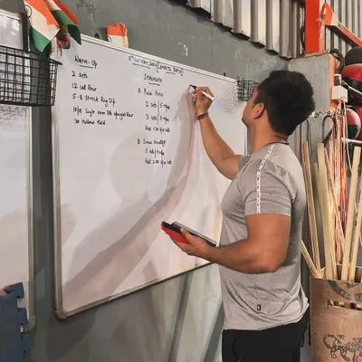 Every workout here is part of a plan. This is me mapping out a session on the whiteboard, detailing everything from the warm-up to the strength components like bench press and deadlifts. My approach to martial arts and combat fitness is structured to ensure you are always progressing safely and effectively.