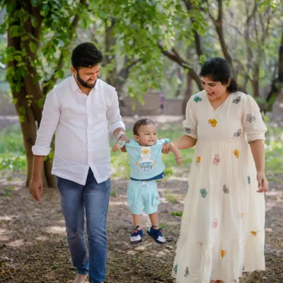 A gentle walk through the park, with mom and dad helping their little one take his first swinging steps. These candid moments are what outdoor family photography is all about.