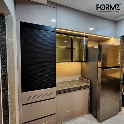 This view highlights the appliance garage with a roller shutter, seamlessly integrated next to the refrigerator. The combination of beige cabinets and granite countertops creates a warm and functional workspace.