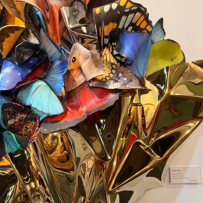 A close-up of "Wings of Resilience." Each polycarbonate butterfly wing is carefully placed to create a layered, three-dimensional effect against the golden steel.