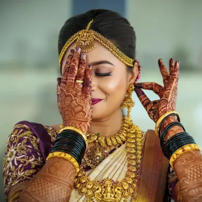 A beautiful bride adorned in a full antique gold temple jewellery set. The intricate details on the necklace, jhumkas, and maang tikka are perfectly highlighted in this shot, showing off her complete bridal radiance.