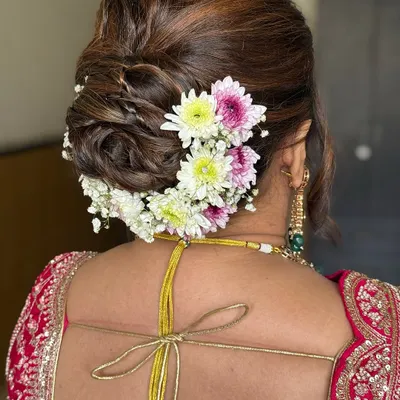 A classic bridal bun adorned with fresh, colorful flowers. This timeless hairstyle adds a touch of elegance and tradition to any bridal look.