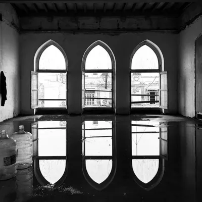 Reflections in a flooded room of a new project site. Water and light reveal the elegant arches of the windows, hinting at the building's past and offering a moment of poetry before the rigorous work of restoration begins.