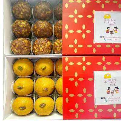 Boxes of our fresh homemade laddoos ready for delivery. This image shows our sugar-free Date and Walnut laddoos alongside our classic Besan Laddoos, packed in festive red boxes.