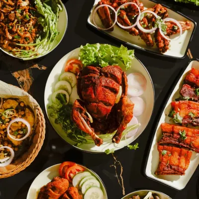 A beautiful spread of our chicken and other non-veg dishes. The centerpiece is a whole fried chicken, surrounded by chicken legs, pork, and fresh salads.