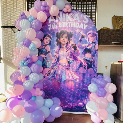 A cool and edgy 'Huntrix' themed backdrop for Anika's 7th birthday, surrounded by a pastel purple and blue balloon garland.
