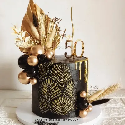 There's something mysteriously captivating about black and gold. This 50th birthday cake features a bold black design with a gold leaf stencil, drip effect, and a cascade of black and gold spheres.