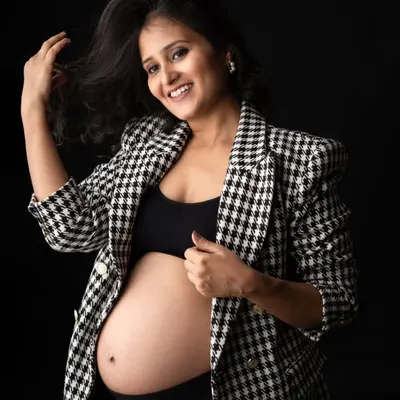 Who says maternity can't be chic? This mom-to-be looks amazing in a trendy houndstooth blazer and a crop top that proudly shows off her baby bump. A modern and stylish look for a studio portrait.