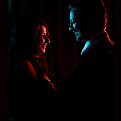 A silhouette portrait of the couple, using dramatic red and blue backlighting to create an intimate and moody reception shot.