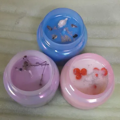 Soft glow, gentle vibes. These iridescent jars are filled with pastel-colored wax and decorated with natural elements like dried flowers and seashells.