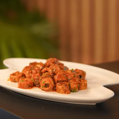 A platter of saucy, sliced seekh kebabs, ready to be served. This shot captures the final moments before a dish goes out to a guest at an event.