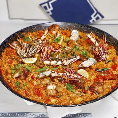 A magnificent seafood paella, overflowing with lobster, prawns, and mussels. This is a dish for sharing, a true celebration of Spanish coastal flavors.