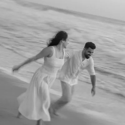 This black and white shot uses motion blur to capture the couple's joyful energy as they run along the shoreline. The lack of color emphasizes their movement and the timeless feeling of a carefree moment by the sea.