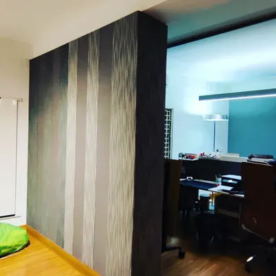 This is a finished acoustic fabric panel wall. The striped pattern adds a decorative element while the material itself effectively absorbs sound, making the adjacent office space quieter.