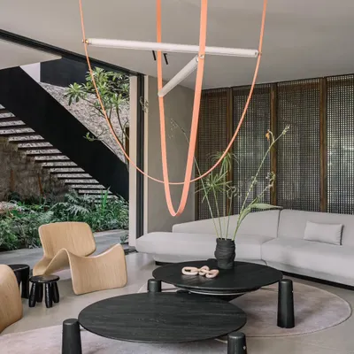 The main living area at GAIA, featuring a dramatic custom light fixture and low-profile, modern furniture. The space opens directly to the outdoors, blurring the line between inside and out.