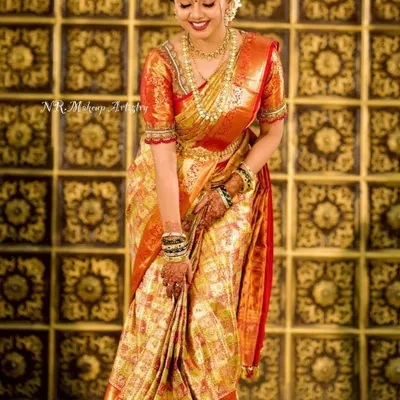 A full-length portrait of a radiant bride in her golden-hued wedding saree. The makeup is kept classic and luminous to complement the grandeur of her attire.