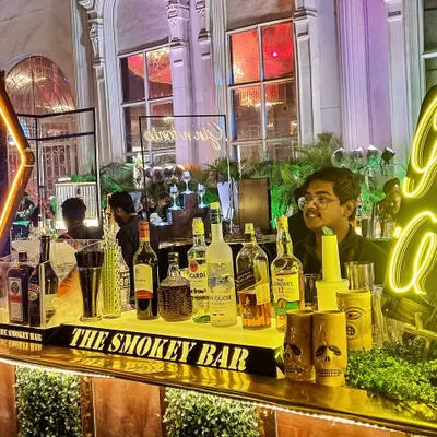 A vibrant 'Gin O'Clock' neon sign sets the mood at this wedding event. I designed this setup with a mix of modern lighting and lush greenery to create an inviting and high-energy gin bar.