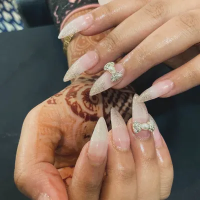 Perfect for a wedding or any special occasion. These stiletto nail extensions feature a beautiful glitter ombré effect and are accented with delicate, pearl-centered 3D rhinestone bows for an extra touch of glam.