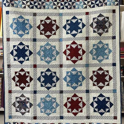 A classic Lone Star quilt in patriotic red, white, and blue. The intricate star pattern is complemented by a border of tiny pinwheel blocks, showcasing a high level of precision piecing.