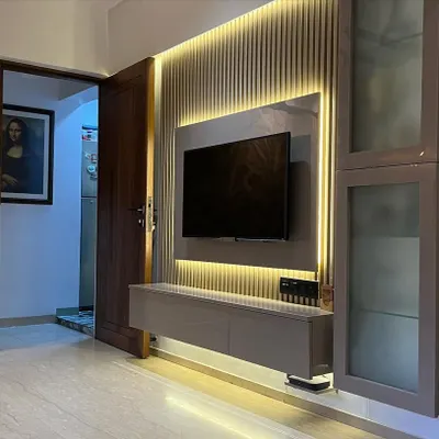 A full view of a modern TV wall unit. The combination of a fluted back panel, ambient lighting, and integrated storage creates a functional and visually appealing focal point in the living room.